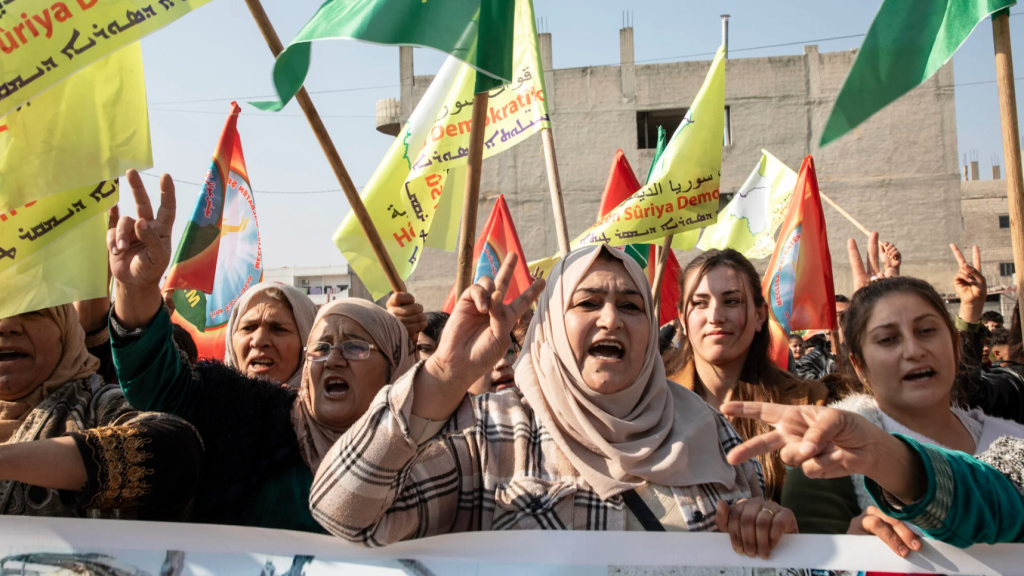 Women lead the front row, raising their voices in protest during a demonstration in Kobane on January 16, condemning Turkey’s attack on a civilian convoy near Tishrin Dam.