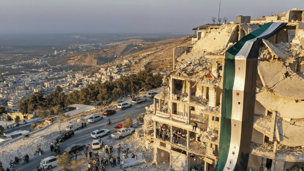 Free Syria flag drapped over ruins