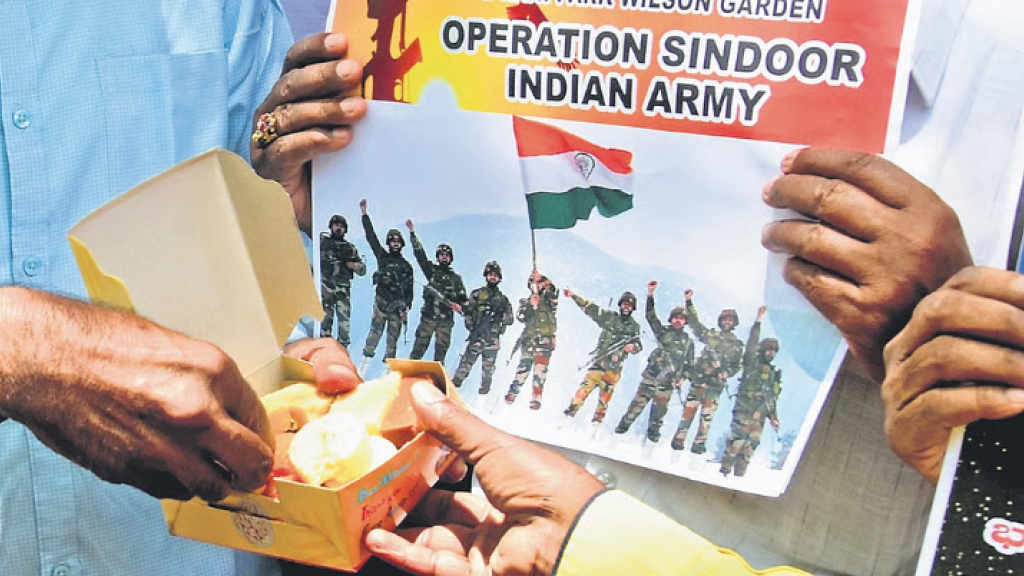 Citizens share a box of sweets and hold up posters celebrating the success of Operation Sindoor in Bengaluru on Wednesday