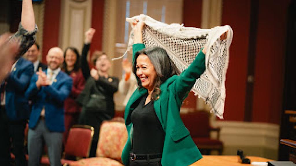 QS parliamentary leader Ruba Ghazal, of Palestinian origin, hoists a keffiyeh at the swearing-in of the party’s MNAs at Quebec's National Assembly.