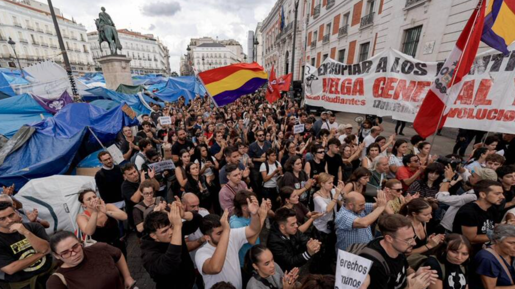 Demonstrators protesting Spain's housing and rental crisis, on Madrid's Puerta del Sol with the protest encampment visible in the background (2 October 2026)