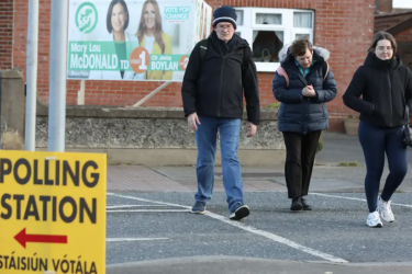 People walk past a polling station sign in Cabra, Dublin, ahead of Ireland’s general election on Friday. 