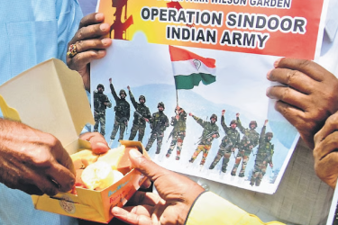 Citizens share a box of sweets and hold up posters celebrating the success of Operation Sindoor in Bengaluru on Wednesday